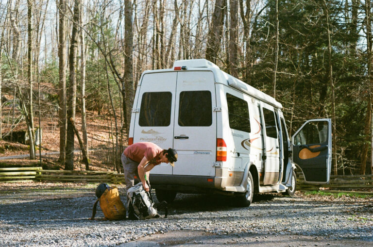 a man with a backpack next to a Class B campervan