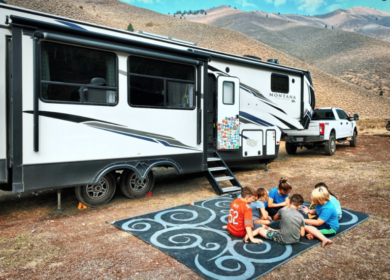 kids sitting in front of a fifth wheel trailer