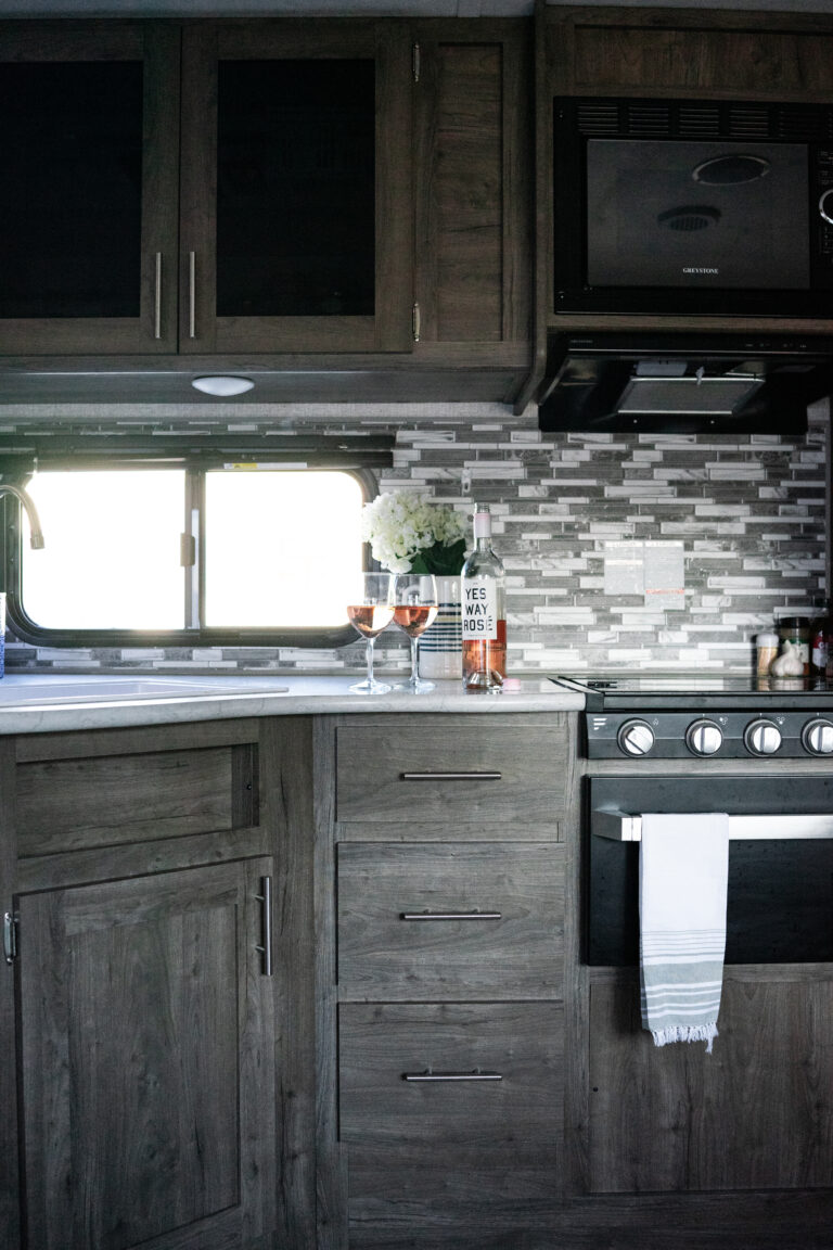 a kitchen sink with a bottle of wine and glasses