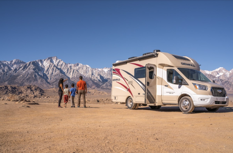 a family next to a Class C RV gazing at the mountains