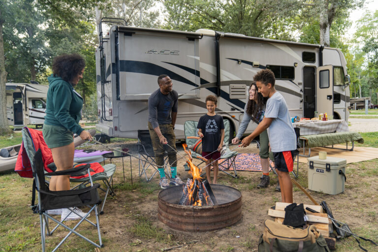 a family next to an RV set up to camp