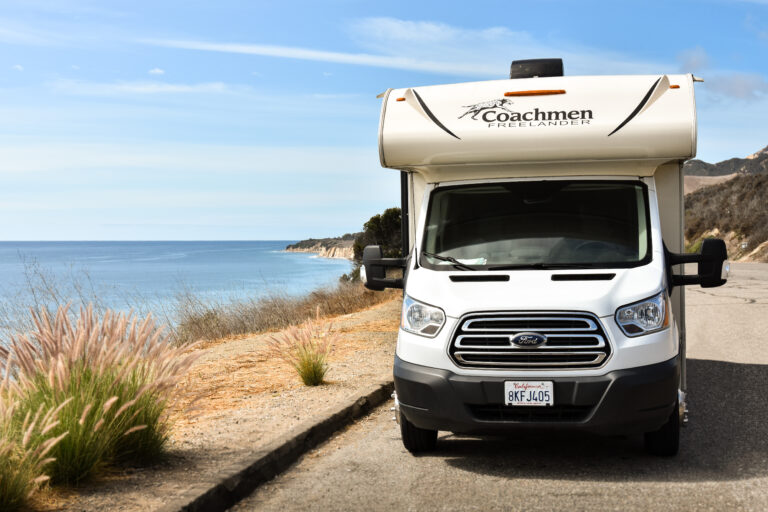 Class C camper next to an ocean