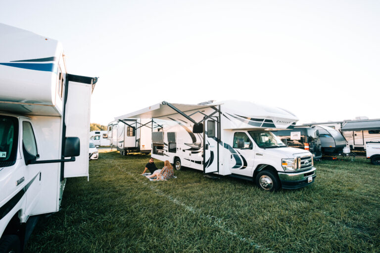 a Class C camper set up with a couple on the grass in front