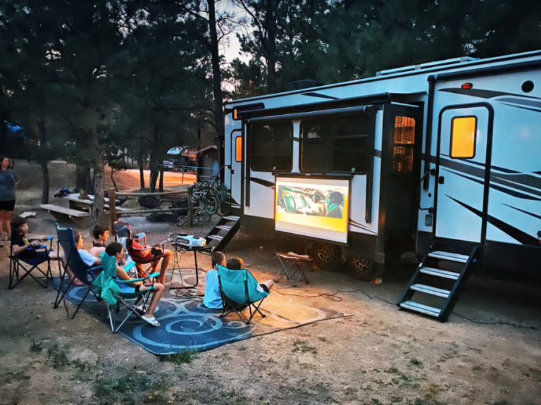 family outside watching TV by an RV