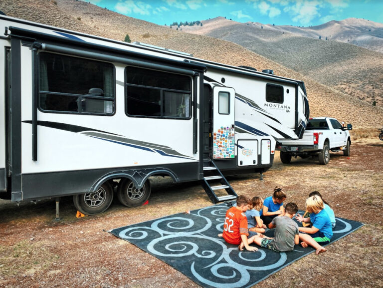 a fifth wheel trailer parked with kids in front