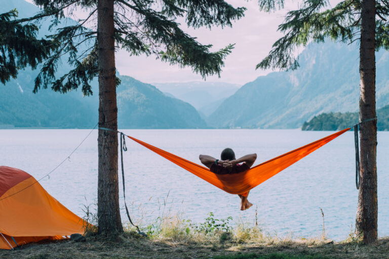 a person relaxing in a hammock next to a lake