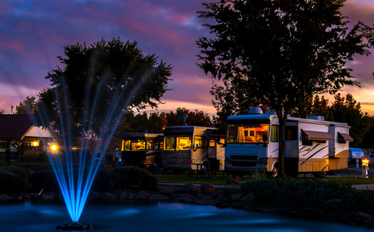 an RV resort at night with a fountain in the foreground