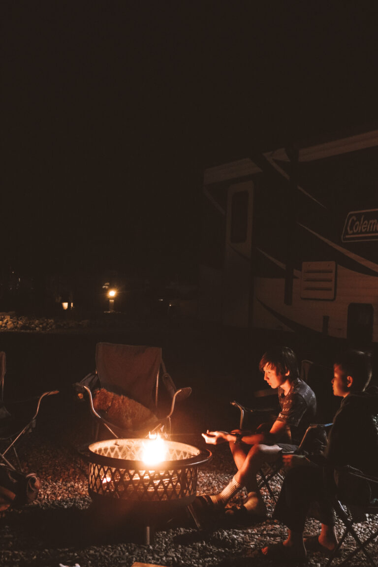 people around a campfire next to an RV
