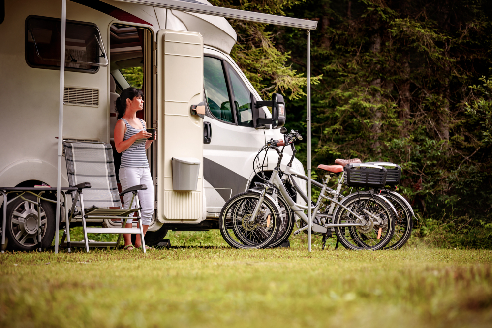 a woman relaxing by a camper with bikes nearby