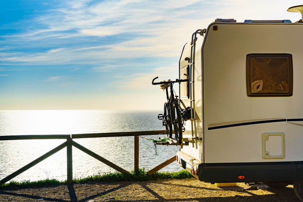 an RV camper with bikes attached parked by the beach