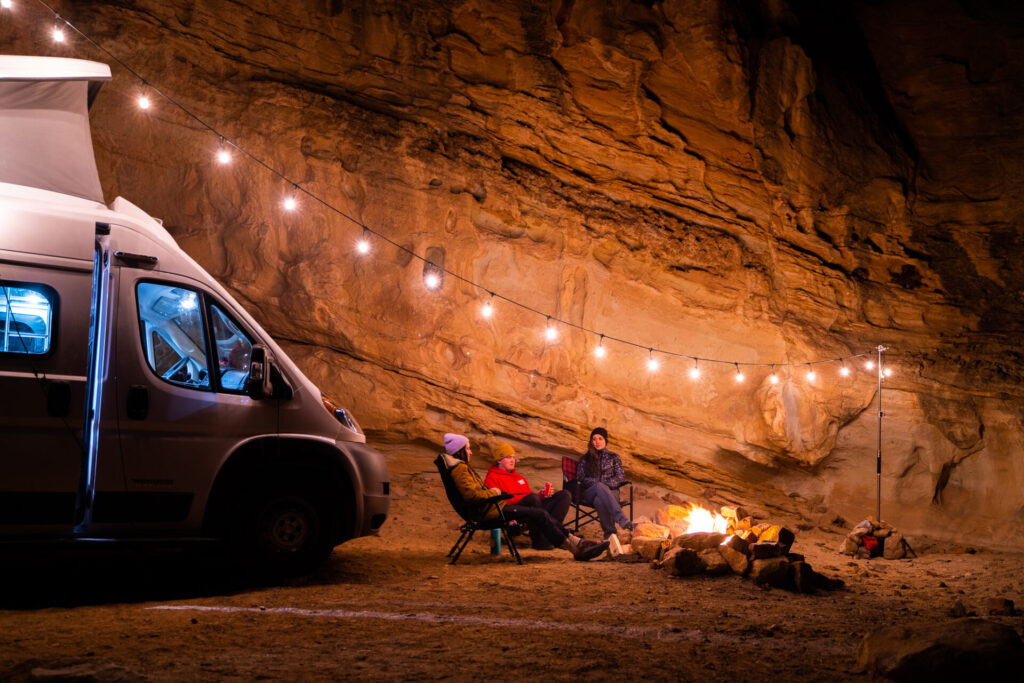 a family relaxing near their Class B camper with a campfire
