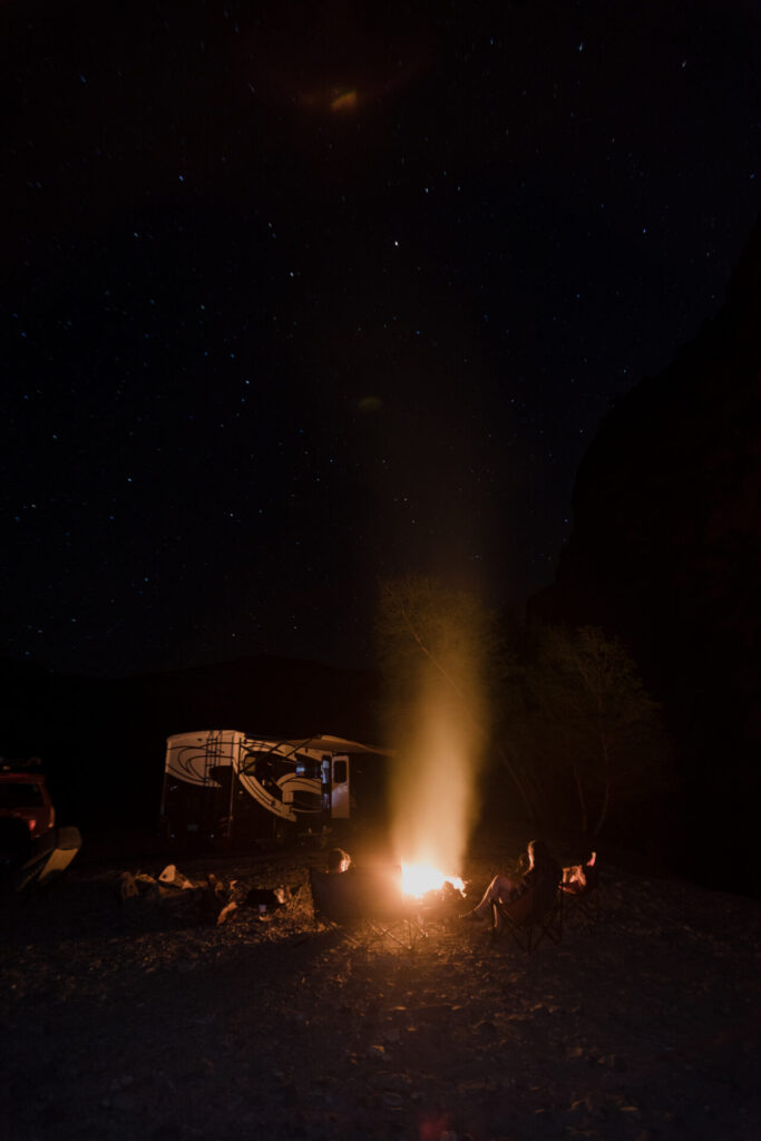 people at an RV around a campfire