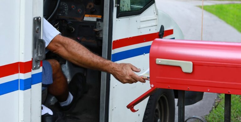 a postal worker putting mail in a mailbox
