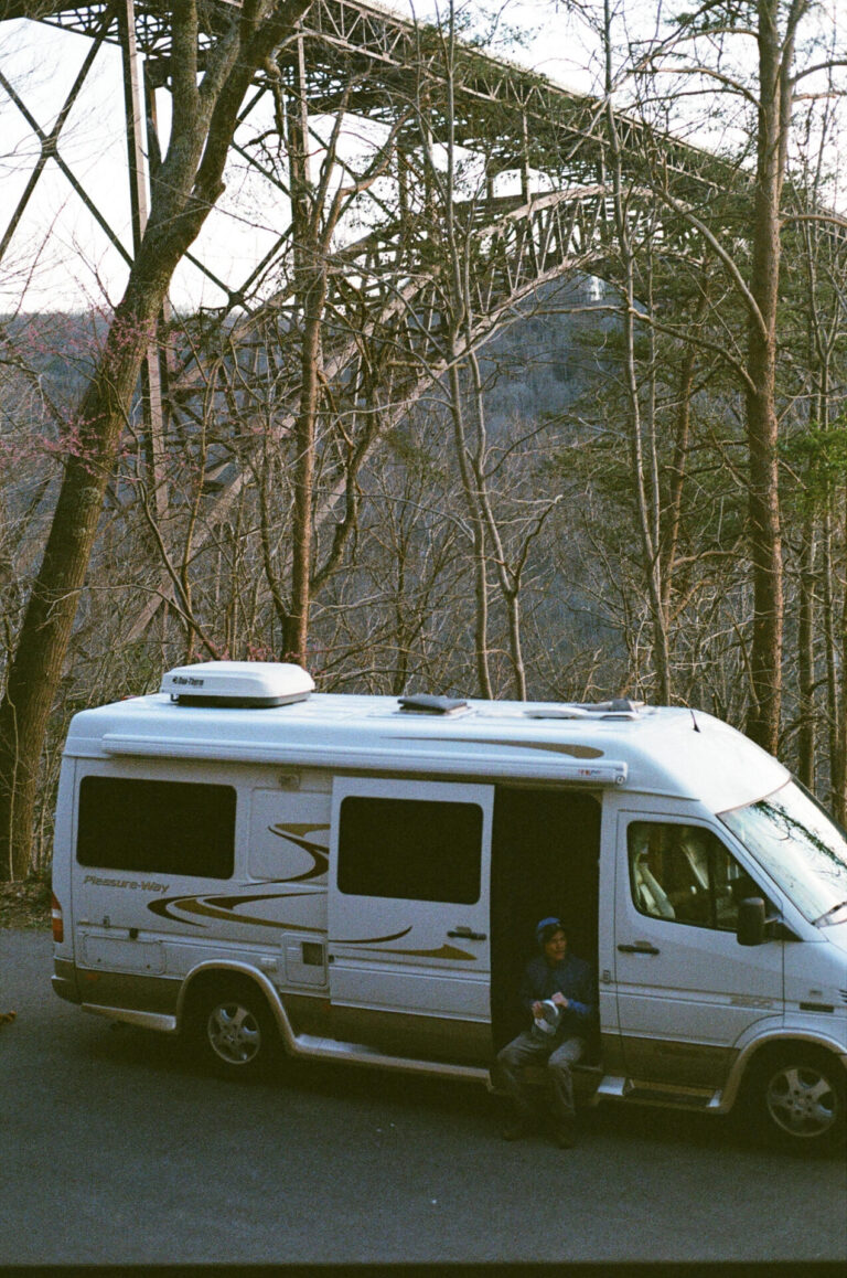 a Class B camper under a bridge