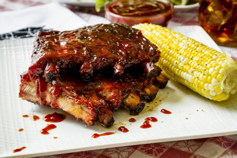 barbeque ribs drenched in sauce with corn