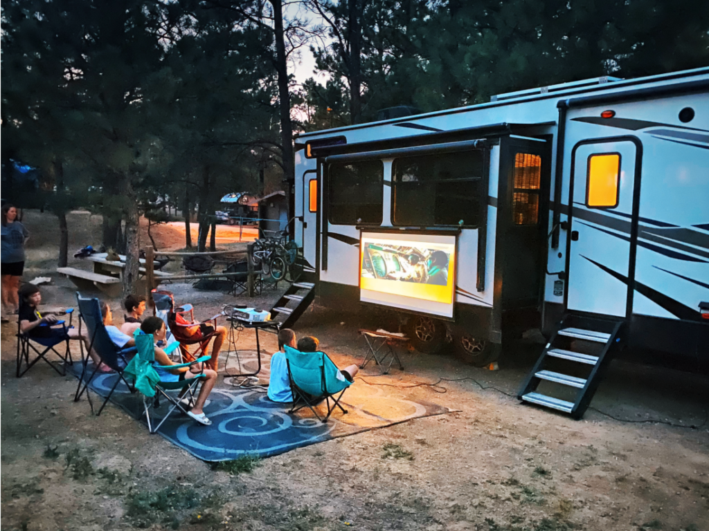 a family watching a movie on the side of their RV