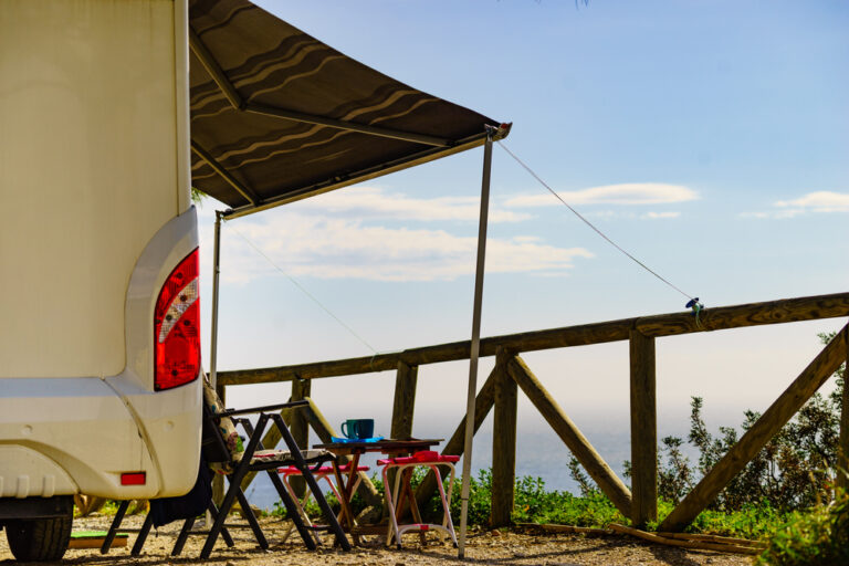 An RV awning tied to a fence and looking over a scenic view