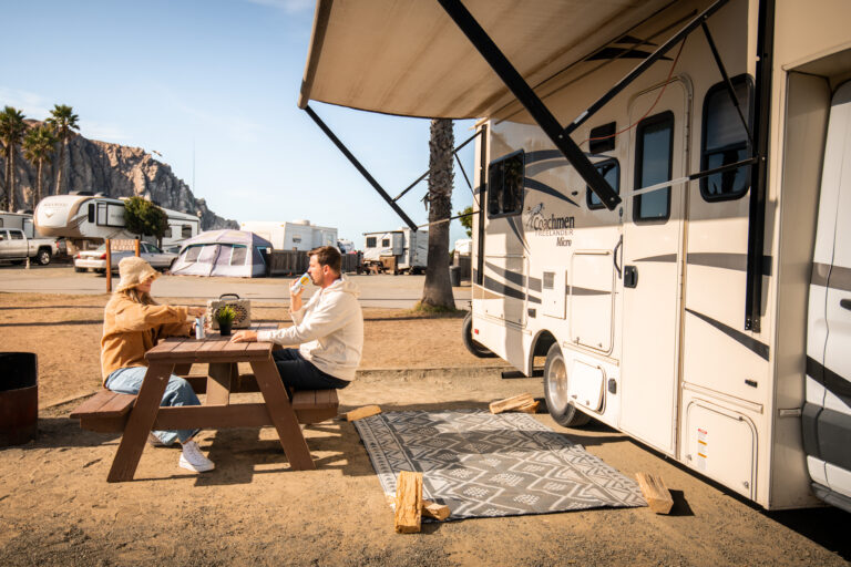A couple eating at a picnic table outside their RV