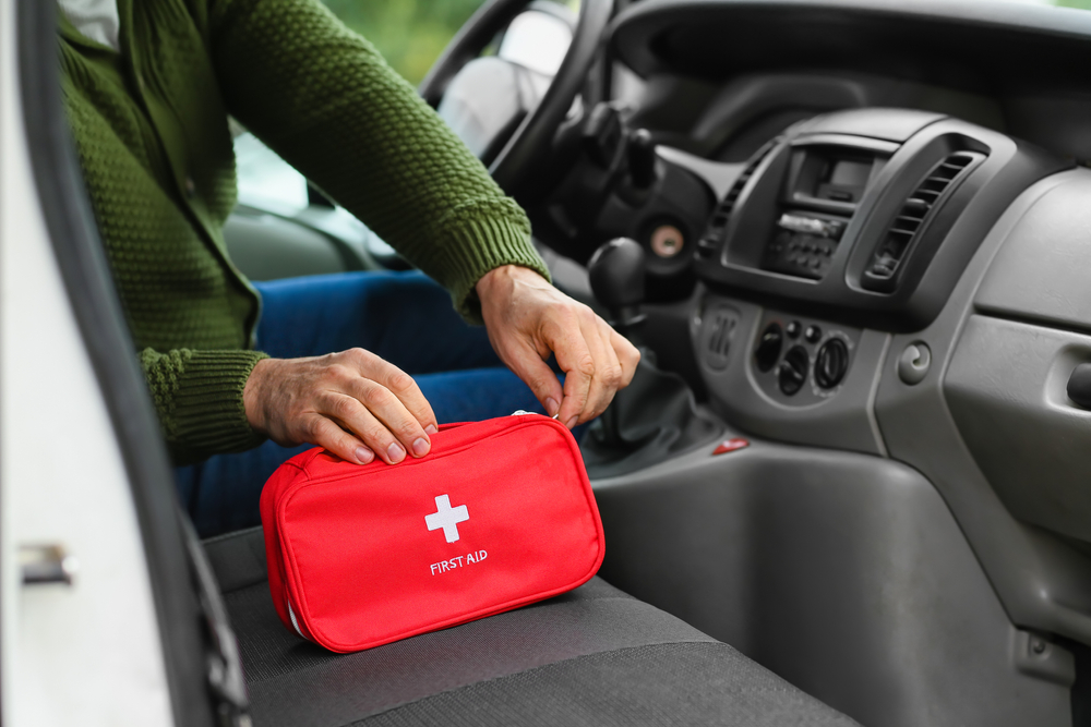 A man in a car unzipping a First Aid kit