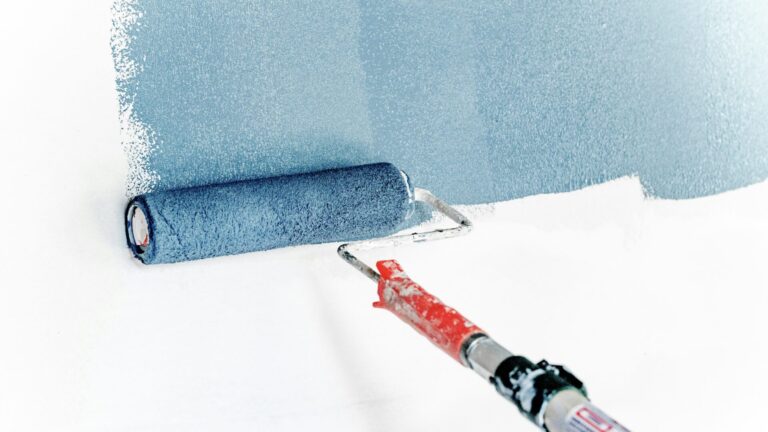 Paint roller painting wall blue. Painting is a great RV renovation idea.
