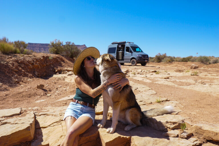 a woman hugging her dog in front of a campervan