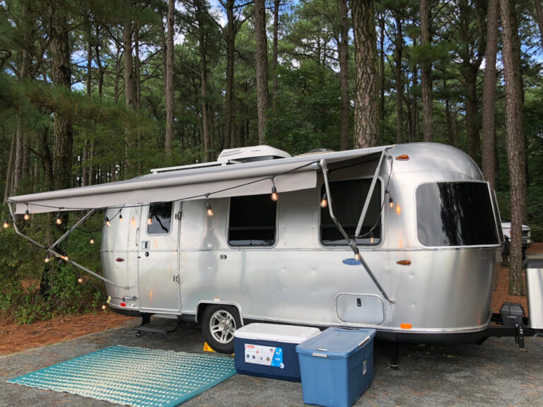 an Airstream trailer with fairy lights around the outside