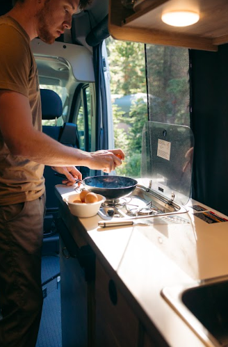 a man cooking breakfast in an RV