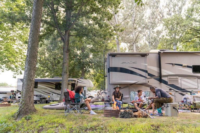 A group of people around a campfire in front of an RV