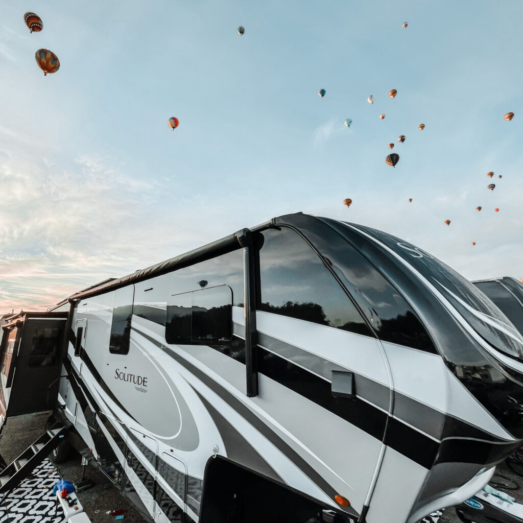 a travel trailer with hot air balloons in the background