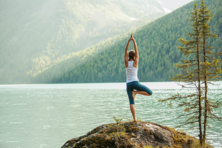 A woman doing a yoga pose on a rock
