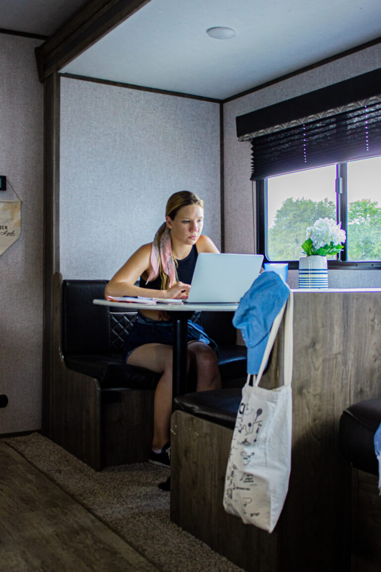 a woman at an RV table working on a computer