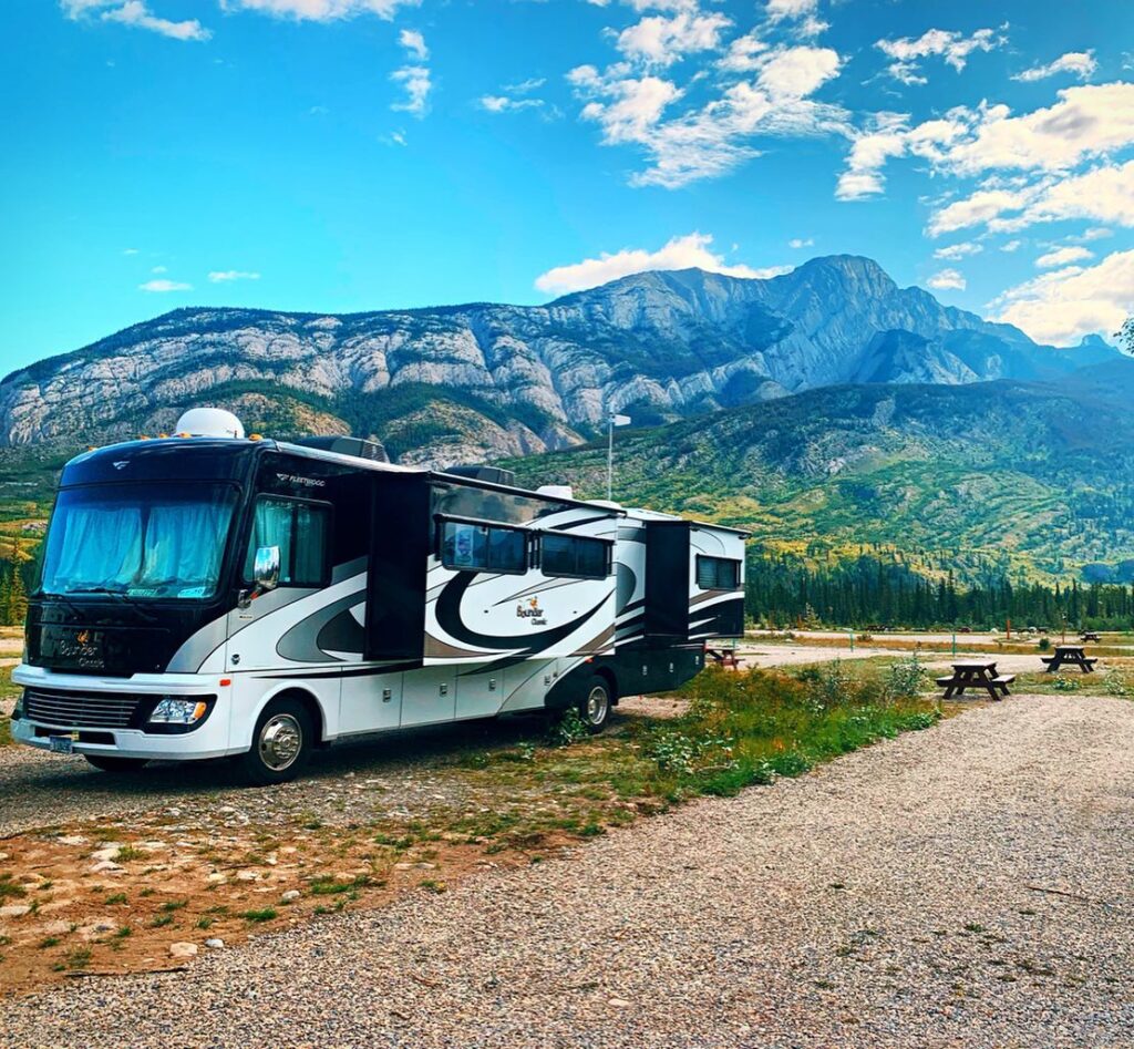 A Class A RV set up in front of a mountain