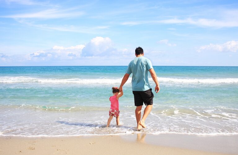 a dad and daughter walking along a beach
