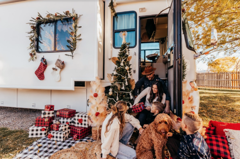 An RV decorated for Christmas with family in front