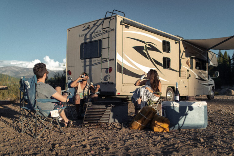 friends relaxing in front of a firepit near an RV