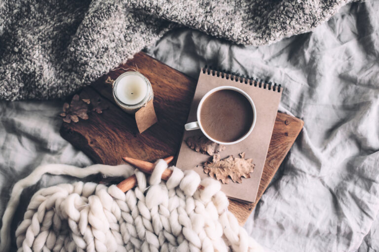 knitting, a cup of coffee, and a candle giving a hygge feel