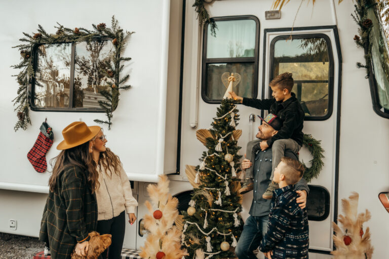 A family around a Christmas tree in front of an RV