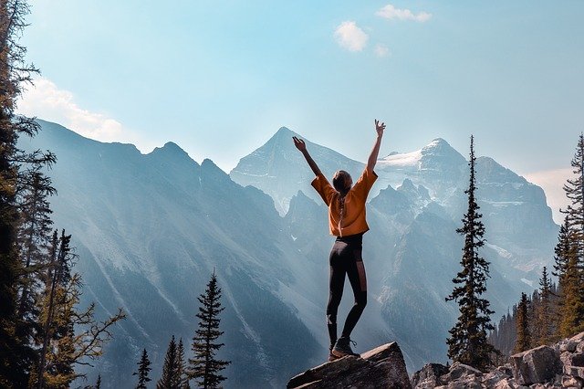 person raising their hands victoriously while hiking a mountain