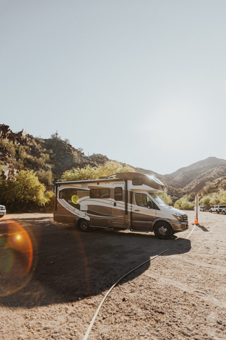 an RV parked in a lot with the sun shining behind