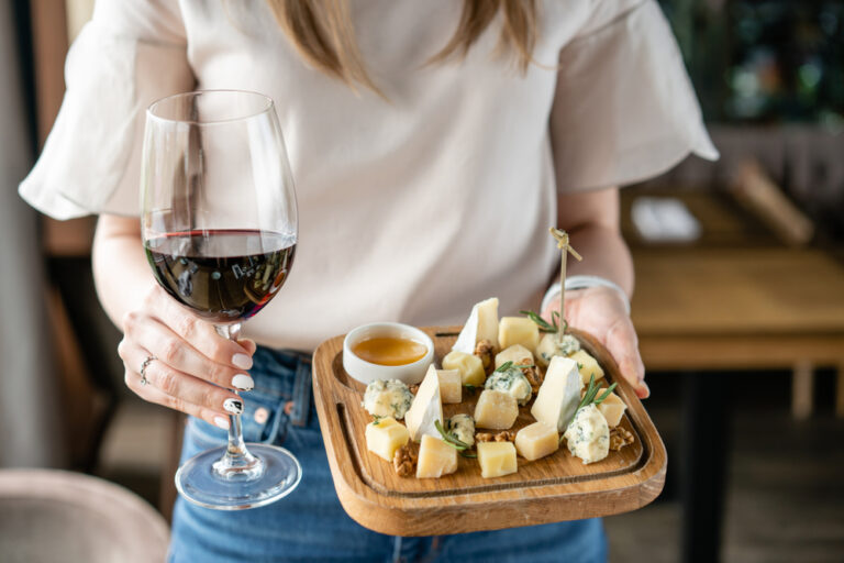 a woman holding a glass of wine and a cheese board