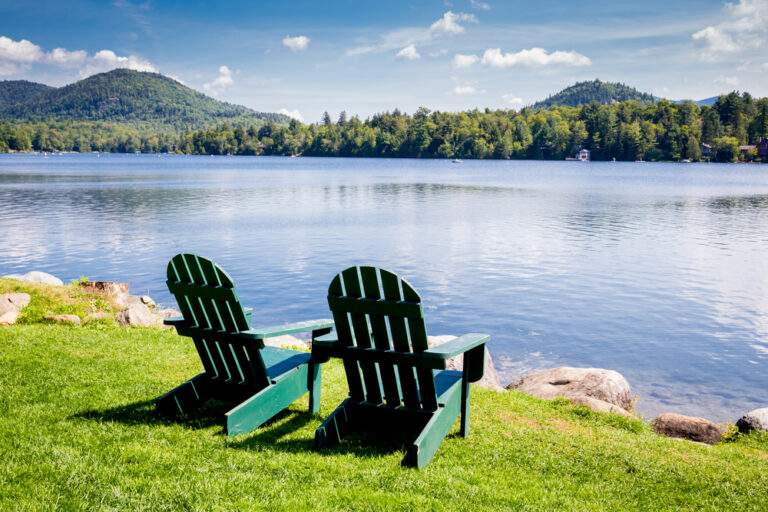two chairs next to a serene lake