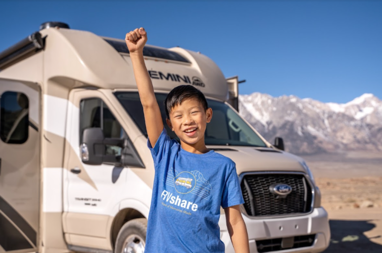 A kid standing in front of an RV cheering