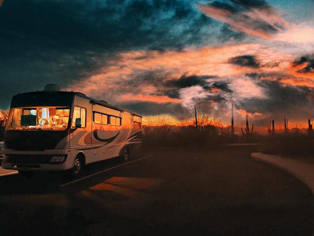 An RV parked with the sun setting behind