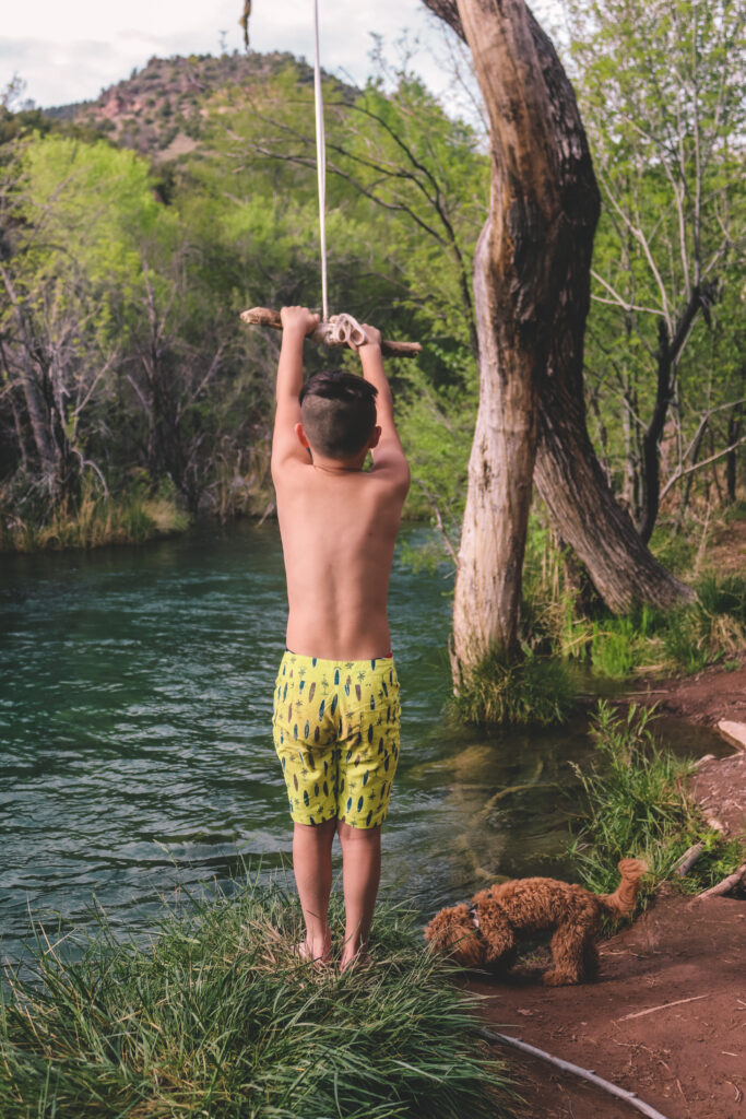A kid jumping from a rope swing into water