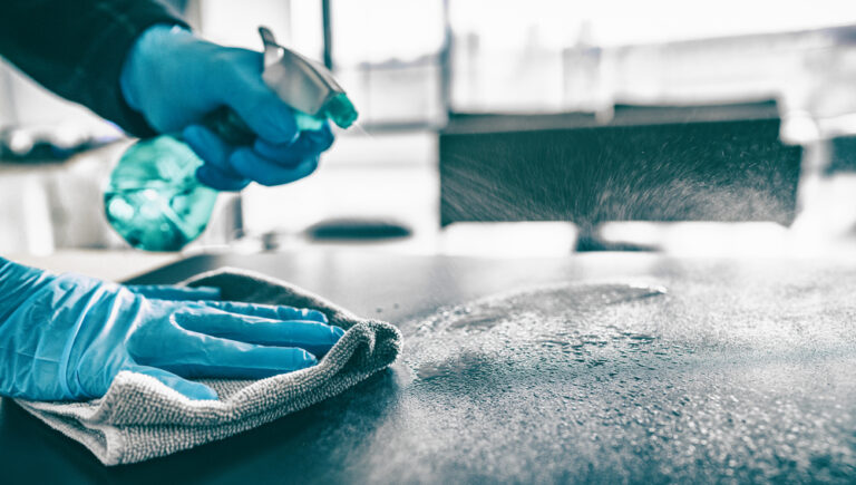 a person wearing gloves and cleaning a counter