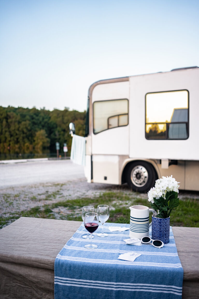 an RV in the background of a picnic table with wine