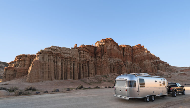 An Airstream trailer next to a red rock desert