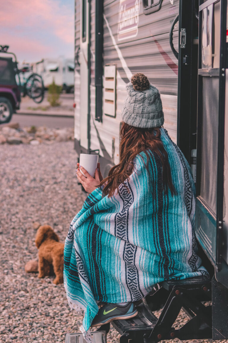 a woman and dog sitting on the steps of a travel trailer