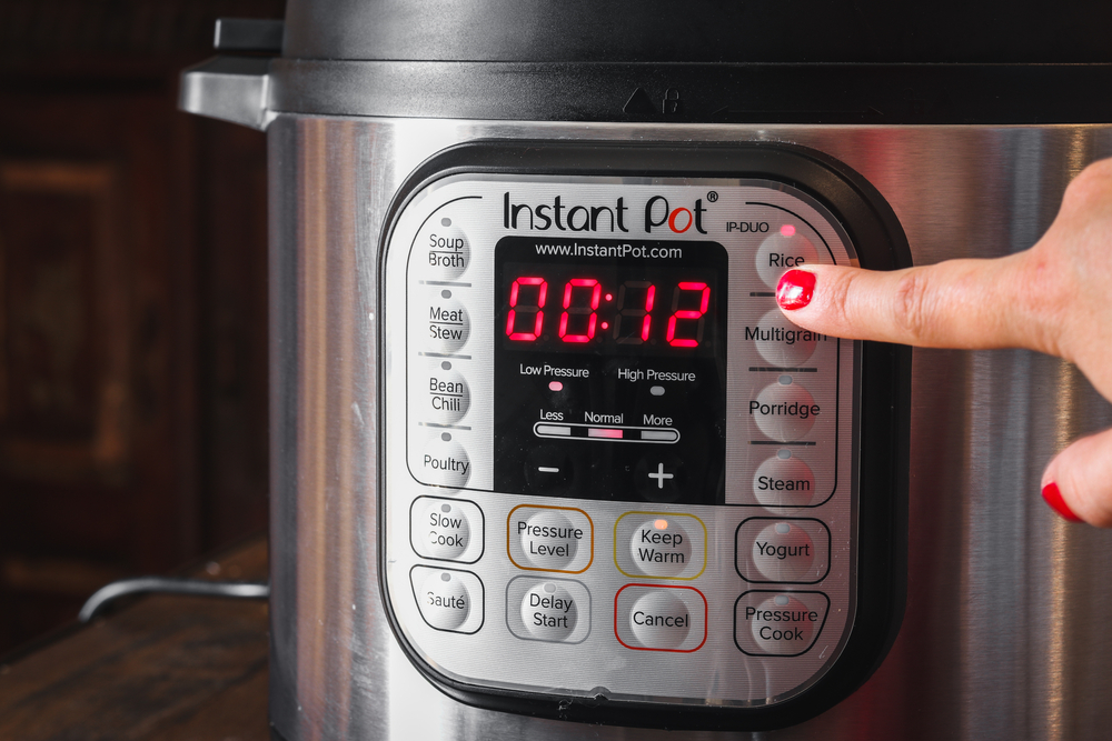 A woman pushing a button on an Instant Pot