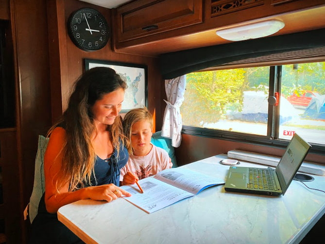 A woman and child doing schoolwork in an RV